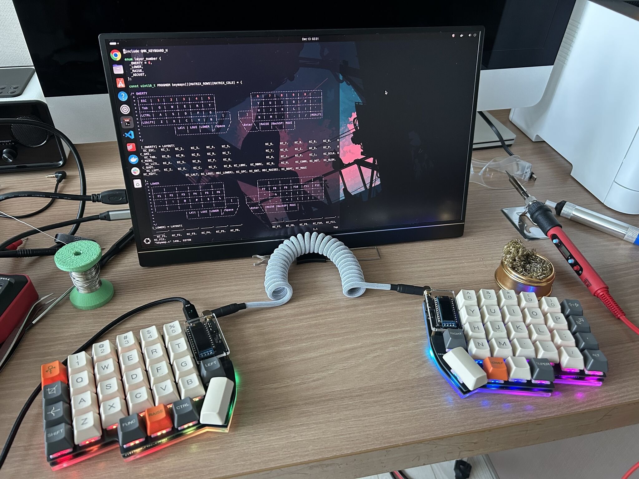 The finished Lily58 Pro on my desk, with the keymap source open on screen and the soldering station still set up beside it.
